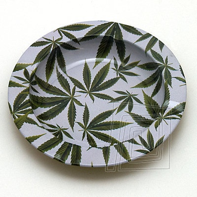 Klasick kovov popolnk bielej farby, v tvare misky so irokm okrajom. Popolnk zdoben zelenmi cannabisovmi listami.